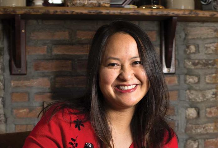 Photo of Marissa Aroy seated in front of a hearth